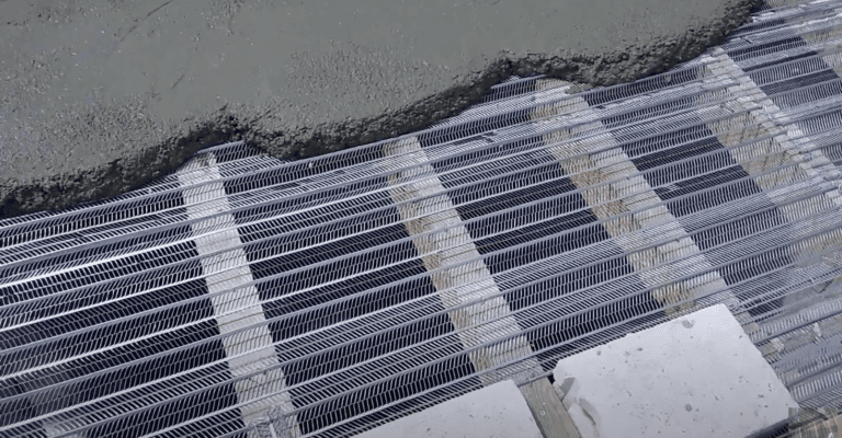 Se está vertiendo hormigón fresco sobre una armadura de malla metálica, con soportes de madera visibles debajo. La imagen muestra el proceso de hormigonado durante el SUMINISTRO E INSTALACION DE FRANJAS CORTAFUEGOS en construcción.