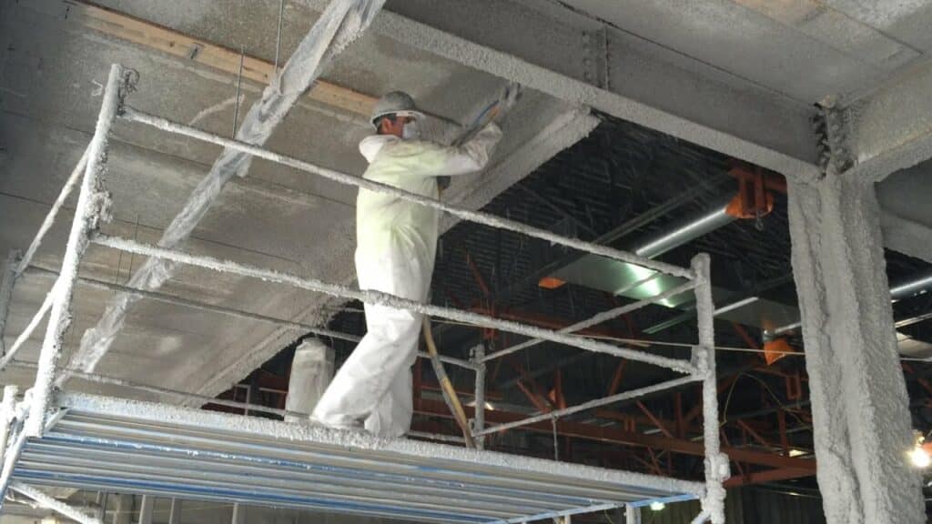 Operario aplicando mortero ign&iacute;fugo proyectado en una nave industrial